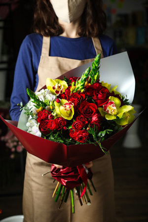 A woman holds a vibrant bouquet of red and yellow flowers, with copy space.の写真素材