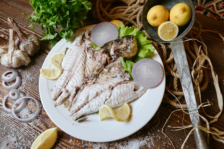A white plate is presented with a delicious fish dish topped with fresh lemons.