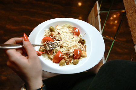 A woman is seen eating a bowl of food using a fork.