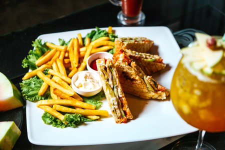 A white plate is filled with crispy French fries and a delicious sandwich.