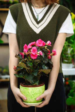 A woman delicately holds a potted plant, providing an opportunity for copy space.の写真素材