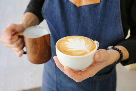 A person holds a cup of coffee in their hands.の写真素材
