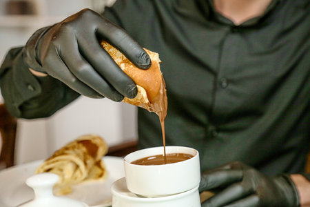 A person wearing black gloves dips an object into a cup.の写真素材