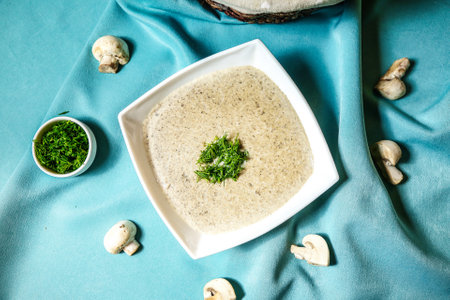 A bowl filled with delicious and creamy broccoli soup placed on a vibrant blue cloth.の写真素材