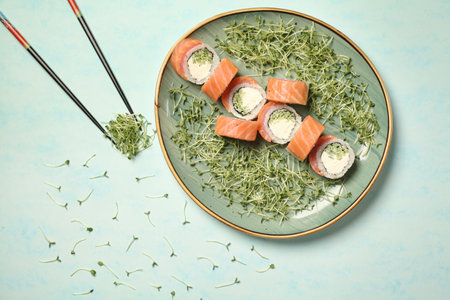A plate displaying a variety of freshly prepared sushi rolls and sashimi, accompanied by a pair of wooden chopsticks.の写真素材