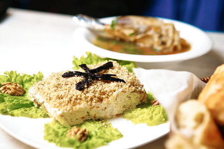 A white plate topped with food is placed next to a bowl of soup.