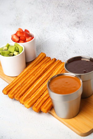 A mouthwatering plate of churros served with an assortment of flavorful dipping sauces on a wooden...