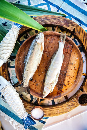 A wooden plate with a fish resting on top, placed on a table.