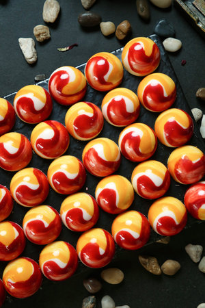 A table is adorned with a multitude of red and yellow marbles, creating a vibrant and eye-catching...