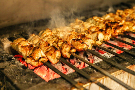 A close-up view of various types of food cooking on a hot grill, generating sizzling sounds and emitting aromatic smoke.の写真素材
