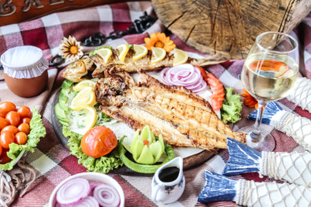 A delicious plate of freshly cooked fish and vibrant vegetables served on a wooden table.の写真素材
