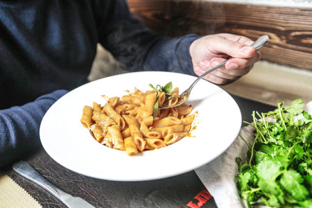 A person holds a fork in a bowl filled with delicious pasta.