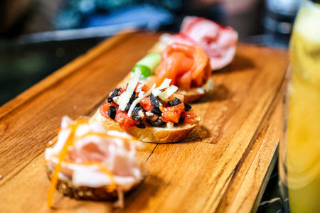 A wooden cutting board showcases various toppings arranged on thinly sliced bread.の写真素材