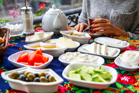 A woman is seen sitting at a table surrounded by an assortment of bowls filled with a variety of delicious foods.の写真素材