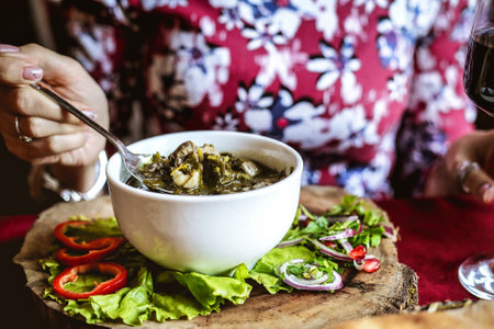 A woman enjoys a meal as she eats a bowl of food and sips on a glass of wine.の写真素材
