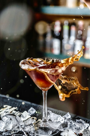 A person pours a drink into a martini glass, creating a swirling motion as the liquid fills the glass.の写真素材