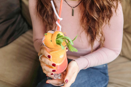 A woman seated on a couch, holding a beverage in her hand.の写真素材