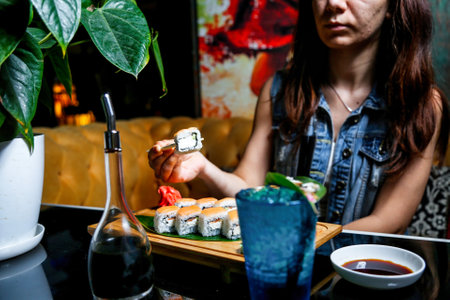 A woman sits at a table, enjoying a plate of sushi.の写真素材
