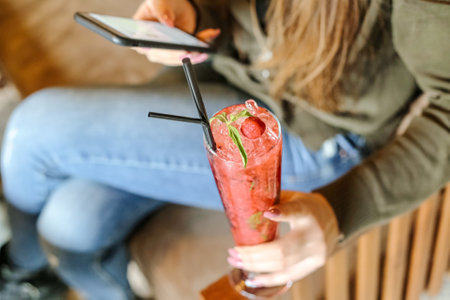 A woman sits on a chair, holding a drink in her hand.の写真素材