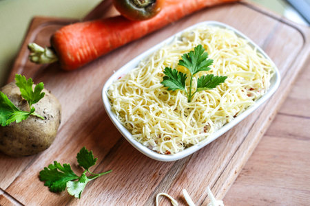A bowl of noodles and carrots neatly arranged on a wooden cutting board.の写真素材