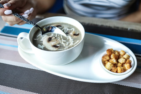 A person is shown holding a spoon in a bowl of soup.の写真素材