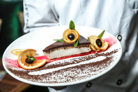 A person holds a plate with a delicious piece of cake on it.の写真素材