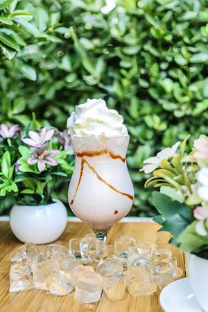 A table with a glass filled with ice cream, surrounded by a clean and tidy setup.