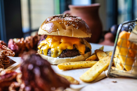 A close-up photo of a cheeseburger and French fries arranged on a table.の写真素材