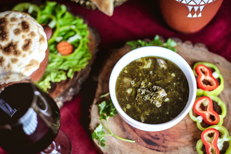 A plate containing a sandwich and a side bowl of salsa, showing a delicious and savory meal.