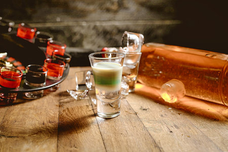 A wooden table featuring glasses filled with various liquids, showing a range of colors and...