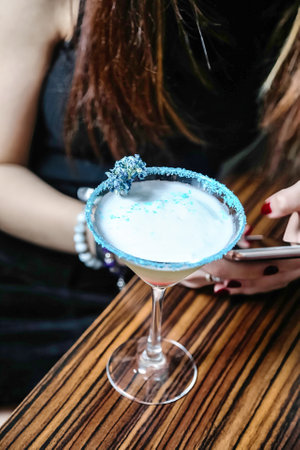 A woman is seated at a table and engrossed in using her cell phone.の写真素材
