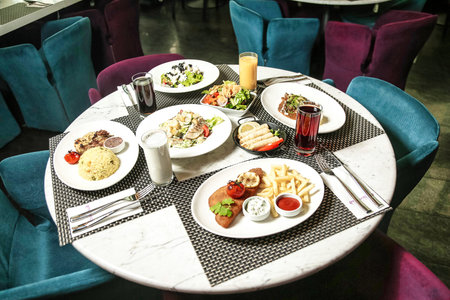 A table covered with plates of food, accompanied by blue chairs.