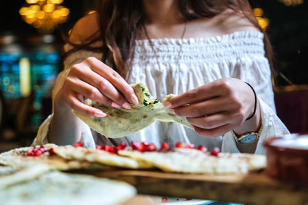 A woman dressed in a white top is seen enjoying a tortilla.の写真素材