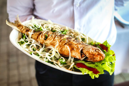 A person holds a plate of food filled with delicious, fresh shrimp.
