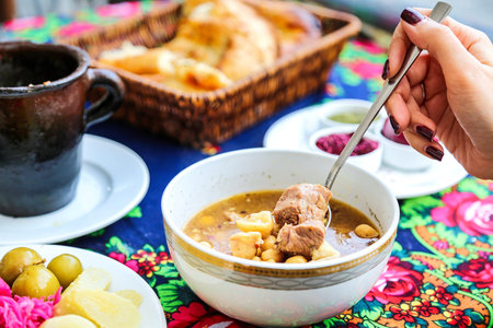 A person is seen eating a bowl of soup using a spoon.
