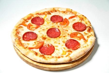 A close-up photo of a mouthwatering pepperoni and pepperoni pizza placed on a wooden plate.の写真素材