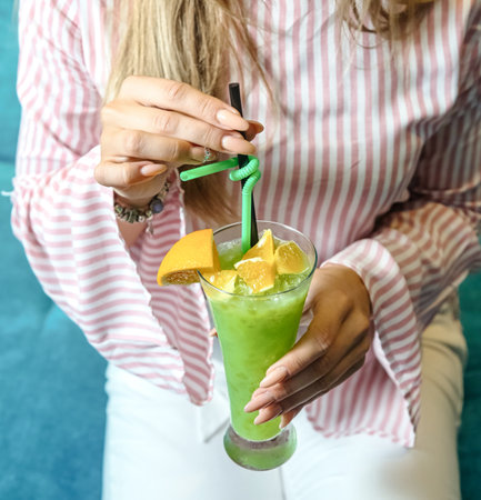 A woman is seen holding a green drink in her hand.の写真素材