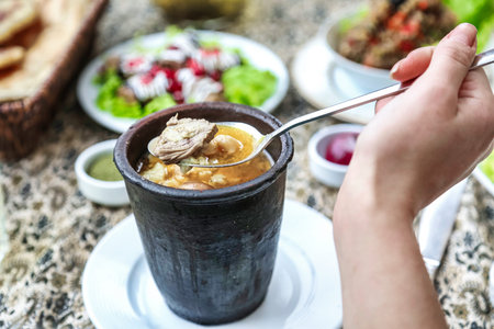 A person holding a spoon above a bowl filled with delicious food.