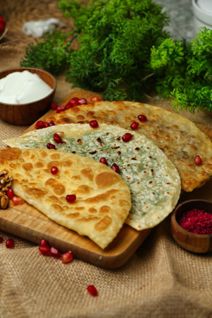 A close-up of three Chebureki, traditional savory pastries, topped with pomegranate seeds and fresh...