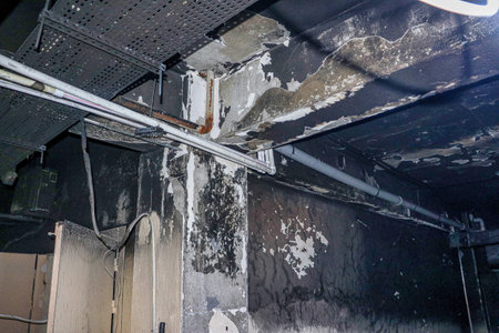 A close-up shot of water damage and soot on a ceiling and wall.