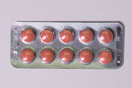 A full blister pack of red pills on a white surface.