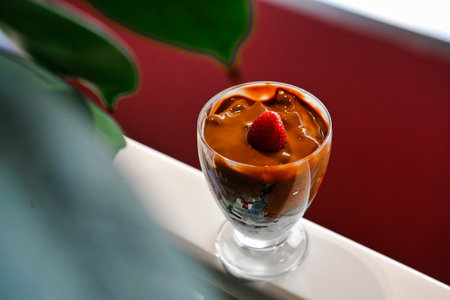 A close-up of a chocolate dessert with a strawberry topping in a clear glass.の写真素材