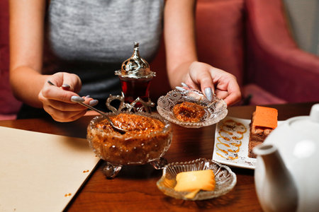 A woman enjoys a sweet dessert with a spoon in a cafe.の写真素材