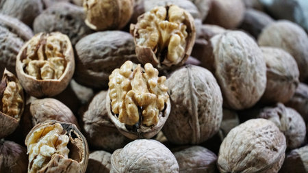 A close-up of shelled walnuts, some with their shells still attached.