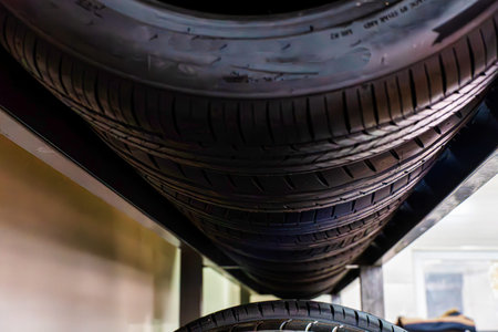 A stack of used tires sits on a metal shelf in a garage.