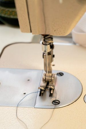 A sewing machine needle is lowered onto fabric in a craft studio, showing the intricate mechanics of...
