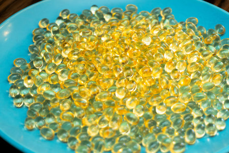 A vibrant blue plate is filled with an assortment of transparent yellow beads that reflect light....
