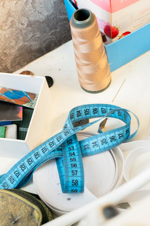 A vibrant workspace features spools of thread, measuring tape, and various crafting materials arranged neatly on a table in soft natural light.の写真素材
