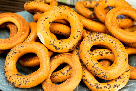 A plate is filled with freshly baked bagels sprinkled with poppy seeds. Their golden-brown color invites to enjoy these delicious treats.の写真素材
