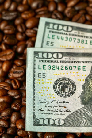 Freshly roasted coffee beans surround two hundred dollar bills, creating a warm and inviting atmosphere perfect for coffee enthusiasts and financial discussions.の写真素材